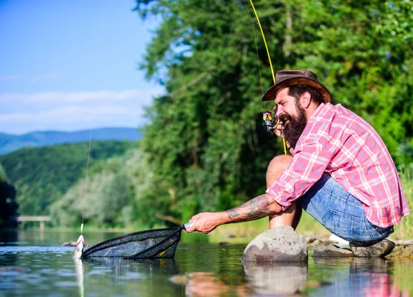 Человек на берегу реки наслаждаться мирным идиллическим ландшафтом во время рыбалки. Объединились с природой. Рыбак рыбалка технику использовать стержень. Человек ловит рыбу. Мужик рыбачит. Успешная рыбалка. Хобби для души — стоковое фото