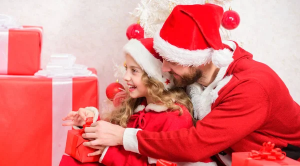 クリスマスの家族の休日。今年はあなたの子供の休日を特別なものにしてください。父のクリスマスのコンセプト。子供へのクリスマスプレゼント。サンタの衣装でお父さんは娘かわいい子供に贈り物を与えます。幸せな子供時代 — ストック写真