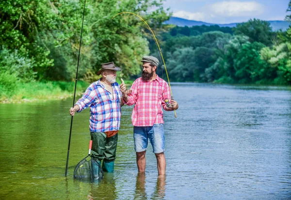 fishing Still Keeps Us Together. hobby and sport activity. Trout bait. two happy fisherman with fishing rods. male friendship. family bonding. father and son fishing. summer weekend. men fisher