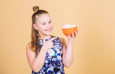 Uzun saçlı çocuk kız tatlılar seviyor ve davranır. Kalori ve diyet. Aç çocuk. Marshmallow mücadelesi. Kız gülümseyen yüz el bej arka planda tatlı marshmallows ile kase tutun. Tatlı diş kavramı