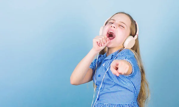 Hay una canción para cada emoción. Adorable cantante amateur de karaoke sobre fondo azul. Lindo niño pequeño haciendo vocal en la canción. Niña cantando la canción jugando en los auriculares, espacio para copiar — Foto de Stock