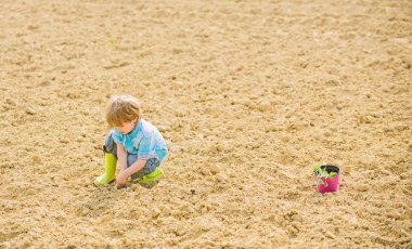 dünya günü. yeni bir hayat. yaz çiftliği. ekoloji ve çevre koruma. mutlu çocuk bahçıvan. botanik işçisi. Bahar mevsimi. küçük çocuk bir çiçek dikim. tarım ve tarım. İşinin tadını çıkarıyor