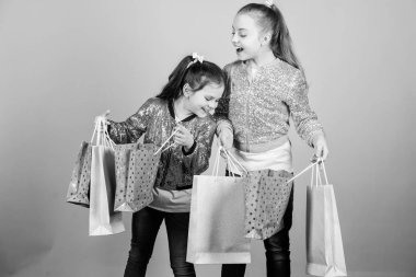Satış ve indirim. Alışveriş günü. Çocuklar demet paketleri tutarlar. Çocuk modası. Daha fazlasını bekle. Daha az öde. Alışveriş çantaları bej arka plan ile Kız kız kardeş arkadaş. Alışveriş ve satın alma. Kara Cuma