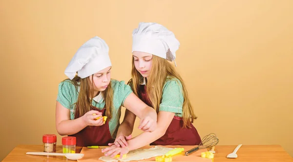 A loro piace cucinare. Adorabili bambine amano cucinare insieme. Bambini piccoli che frequentano corsi di cucina. Cuochi svegli in grembiuli di cottura modellando figure di pasta con stampi — Foto Stock