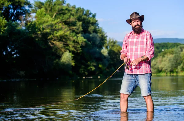 Hobby del pesce della mosca. Attività di pesca estiva. pescatore in acqua di lago. pesca hipster con cucchiaio-esca. pesca d'altura. rilassarsi sulla natura. uomo barbuto maturo con pesce su asta. E 'pronto per la pesca — Foto Stock