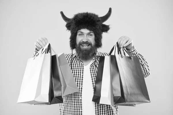 Comprando por placer. Hombre barbudo sonriendo con bolsas de compras. Feliz hipster con cuernos de toro sombrero sosteniendo bolsas de papel después de comprar. Compras es su adicción — Foto de Stock