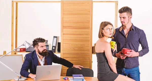 Satisfying desk lunch. Young colleagues talking during work lunch. Two coworkers having tea or coffee for lunch. Business partners talking on lunch break while angry colleague working in background