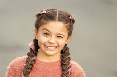 Numara yap ve şaka yap. Neşeli çocuk ifadesi. Her şey yoluna girecek. Kız göz kırpan neşeli, gri bir altyapısı var. Neşeli kız her şeyden memnun. Neşeli ruh hali pozitif duygular