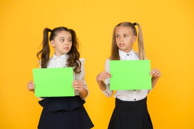 Ev işlerini düşünüyorum. Küçük çocuklar, sınav için boş çarşaflar tutan sarı arka plan üzerinde çalışırlar. Proje çalışması veya araştırma için boş yeşil kağıtları ile küçük kızlar. Kağıt çalışması, kopyalama alanı