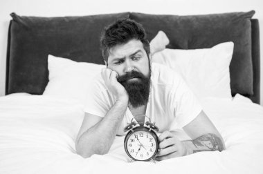 Yatakta depresif bir adam. zaman yönetimi. çalar saat ile yorgun sakallı adam hipster. yatak odasında acımasız uykulu adam. yatakta pijama sakallı olgun erkek. uykuda ve uyanık. enerji ve yorgunluk