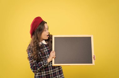 boş tahta ile çocuk. Duyuru. sarı kopya alanı üzerinde parisli çocuk. bere uzun kıvırcık saçlı mutlu kız. Fransız bere küçük kız. duyuru afiş. duyuru kavramı