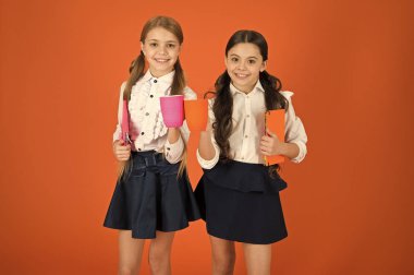 Okul arkadaşları ile içki rahatlatıcı. Öğrenci olmanın tadını çıkarın. Kız çocuklar okul üniforması turuncu arka plan. Kız öğrenci kitap veya Not defteri ve kupa tutun. Okul rutin. Sakin ol molası. Çay molası sırasında içme