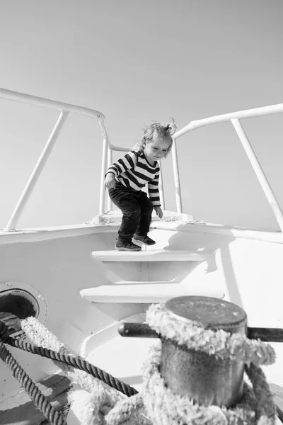happy little boy on yacht. boat trip by sea or ocean. funny kid in striped marine shirt. yacht traveling and wanderlust. summer vacation. childhood happiness. little sailor on yacht boat. yacht child