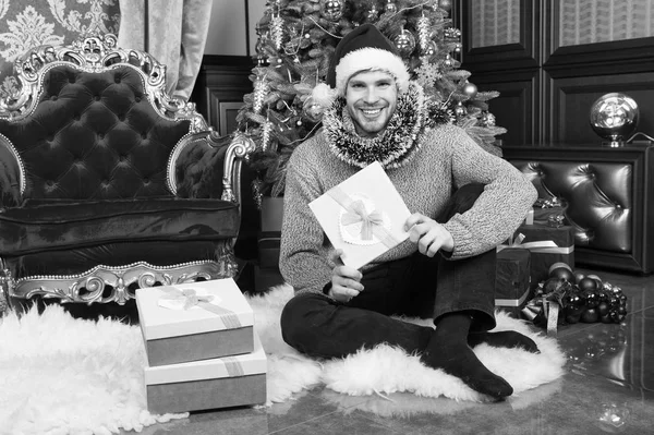 十分なクリスマス プレゼントはありません。男は、家でクリスマスを祝っています。配信クリスマス プレゼント。サンタの帽子の男は、クリスマス プレゼントを保持します。クリスマス ギフト用の箱で幸せな男 — ストック写真