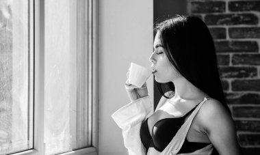 Sabahları içmek için en iyi şey. Lezzetli kahve içeceği ile fincan tutan sevimli kız. Seksi kadın onu içki tarifi zevk. Pretty kadın pencerede sağlıklı sabah içeceği içme