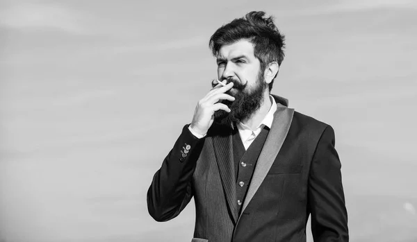 Homem barbudo a fumar cigarro. fumar. Hipster maduro com barba. Hister caucasiano brutal com bigode. Sucesso futuro. Moda formal masculina. Empresário contra o céu. líder e liderança — Fotografia de Stock