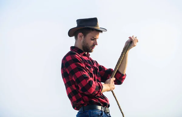 Thoughtful farmer thinking about business. Life at ranch. Cowboy with lasso rope sky background. Ranch worker. Eco farm. Farming concept. Handsome man in hat and rustic style outfit. Keep ranch — Stock Photo, Image