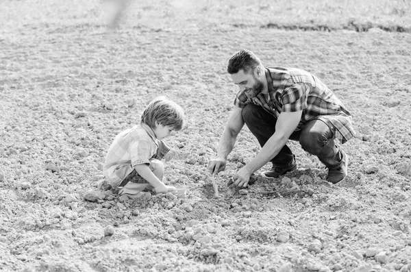 Χαρούμενη γήινη μέρα. Οικογενειακό δέντρο. Πατέρας και γιος φυτεύουν λουλούδια στο έδαφος. Το μικρό παιδί βοηθάει τον πατέρα στη γεωργία. Ημέρα της Γης. νέα ζωή. λιπάσματα εδάφους. πλούσιο φυσικό έδαφος. Οικολογικό αγρόκτημα. Φύλακας φροντίδας — Φωτογραφία Αρχείου
