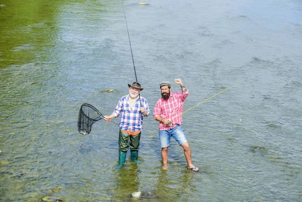 Fim de semana. A pescar juntos. Os homens estão na água. Belo conceito de captura. Equipa de pesca. Pescador feliz com vara de pesca e rede. Atividades hoteleiras e desportivas. Amizade masculina. Pai e filho pesca — Fotografia de Stock