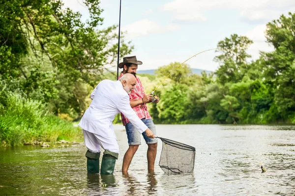 Friends fishing. Perfect weekend. Successful catch. Elegant bearded man and brutal hipster fishing. Hobby and recreation. Relax in natural environment. Summer vacation. Family day. Fishing team