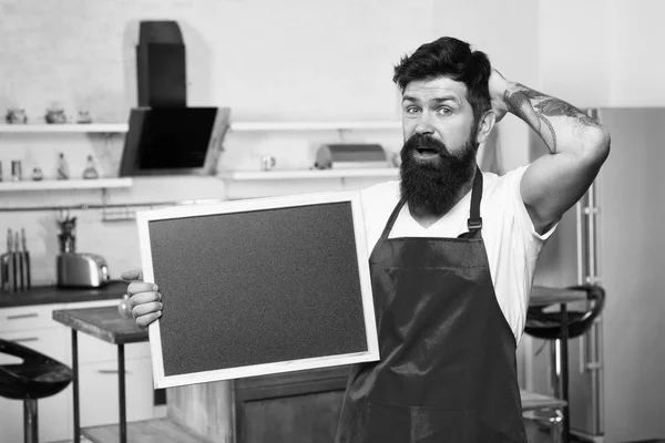 Kitchen hacks concept. Clever ways to organize kitchen. Cook hold blank chalkboard copy space. Secret tips. Useful information. Man bearded hipster red apron stand in kitchen. Kitchen furniture store