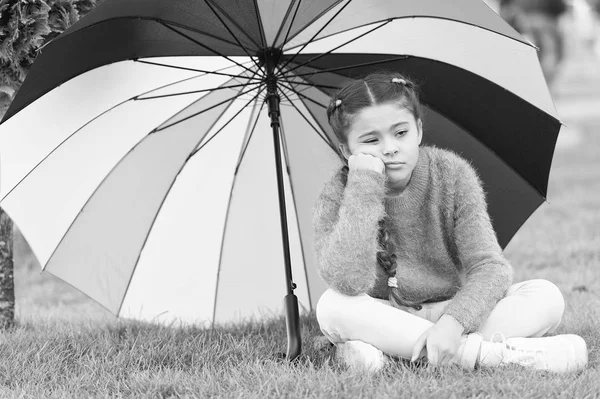 Autumn depression. Spring style. depressive mood in autumn rainy weather. Little girl tired under colorful umbrella. Multicolored umbrella for little happy girl. Rainbow after rain. feeling depressed