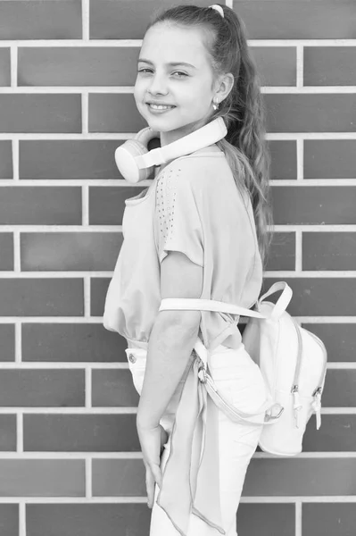 Music of the soul can be heard in the headphones. Cute kid wearing ear stereo headphones on brick wall. Little girl with headphones for listening to music. Small child with modern wireless headphones — Stock Photo, Image