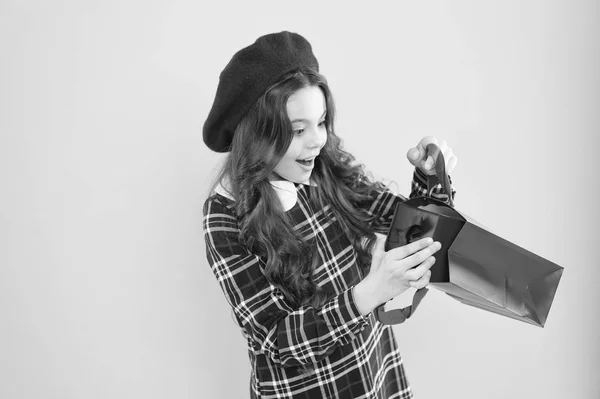 Il regalo perfetto per ogni occasione. Carina bambina che prende il regalo di compleanno su sfondo giallo. Adorabile piccolo bambino con sacchetto di carta con scatola regalo. Dare e ricevere regalo — Foto Stock