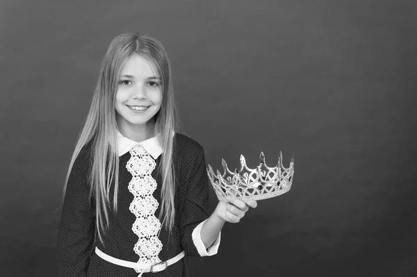 Pageantry of coronation. Little princess. Little pageant girl. Little beauty queen. Adorable little girl child holding crown. Cute and beautiful, copy space. Selfish people concept. Pride and success