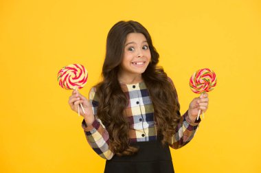 Zararlı yiyecekler. Tatlılara bayılırım. Şeker bağımlılığı. Tatlı şekerli mutlu çocuk. Elinde lolipop tutan çocuk şeker sarısı arka planda. Şekerli mutlu çocuk. Okul beslenmesi. Kalori ve enerji