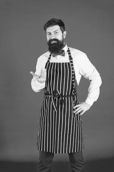 Професіонал на кухні. Чоловік з бородою готує гіпсовий фартух. Кухар хіпстерів готує червоний фон. Бородатий кухар готує. Хіпстер готує будинок або ресторан. Сучасна концепція кафе. Готуємо сучасні страви — стокове фото