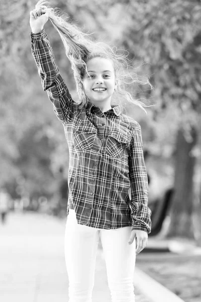 Se sentir confortable et confortable par temps venteux. Traiter avec les cheveux longs par temps venteux. Coiffures à porter par temps venteux. Coiffures coupe-vent. Fille petit enfant mignon profiter de la promenade sur fond de nature jour venteux — Photo