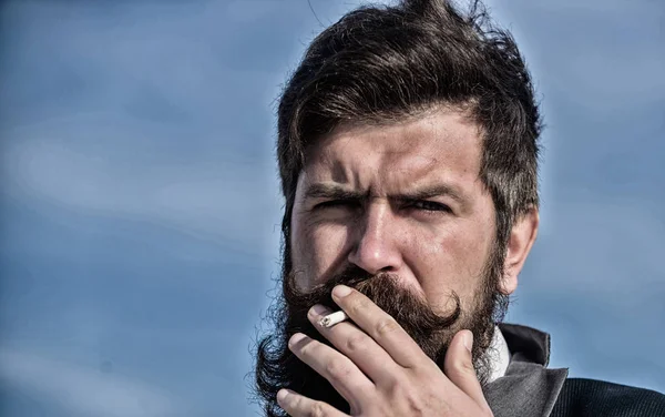 Taking smoking pause. Bearded man smoking cigarette. smoke. brutal caucasian hipster with moustache. Future success. Male formal fashion. Businessman against the sky. Mature hipster with beard