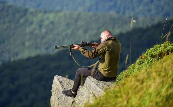 Hunting masculine hobby concept. Regulation of hunting. Focused on target. Hunter hold rifle. Hunter spend leisure hunting. Hunting in mountains. Man brutal gamekeeper nature landscape background