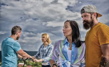 İyi vakit geçiriyor Bisiklet ile çift süre başka bir çift sıkılmış. Çiftler eğlence farklı şekilde gökyüzü arka plan harcamak. Bisiklet kiralayıp ve eğlenin. Bisiklet kiralama hizmeti kavramı. Kız için bisiklet almak