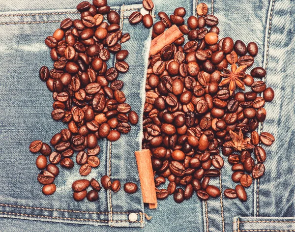 Degree of roasting coffee beans. Texture and background concept. Fresh roasted coffee close up. Beans and spices in jeans pocket. Coffee for inspiration and energy charge. Coffee shop or store