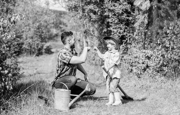 Menino pequeno ajuda pai na agricultura. Eco fazenda. Pai e filho de chapéu de cowboy no rancho. use regador e panela. Equipamento de jardim. Feliz Dia da Terra. Viveiro de árvores genealógicas. dia das crianças — Fotografia de Stock