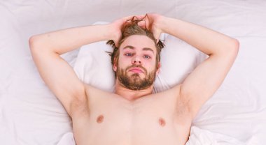 Adam yatakta geriniyor. Genç adamın yatakta gerindiğini gösteren bir resim. Yatakta dinlenen adam..
