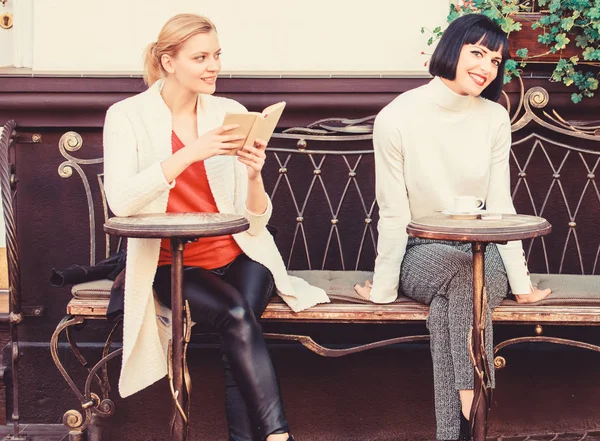 Lesen inspirierendes Buch. Freundinnen sitzen auf der Café-Terrasse und trinken Kaffee. Frauenliteratur. Selbstverbesserung und Bildung. Das populäre Bestseller-Buch. Buch, das jedes Mädchen lesen sollte — Stockfoto