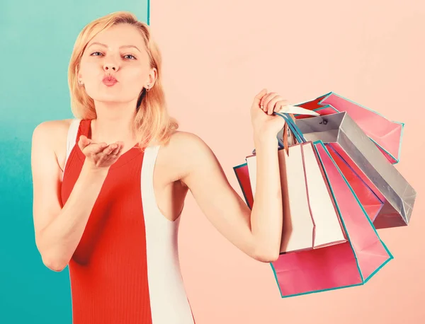 女孩对购物很满意。成功购物销售的提示。女孩喜欢购物或刚刚得到生日礼物。女人红色礼服举行束购物袋蓝色粉红色背景。购买您想要的一切 — 图库照片
