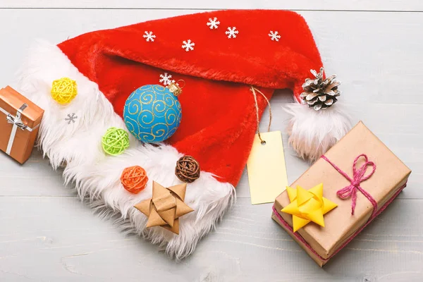 新年和圣诞装饰品。圣诞老人帽子和圣诞礼品盒。圣诞老人送的圣诞礼物圣诞老人帽子白色背景顶视图。气氛就是细节。寒假属性 — 图库照片