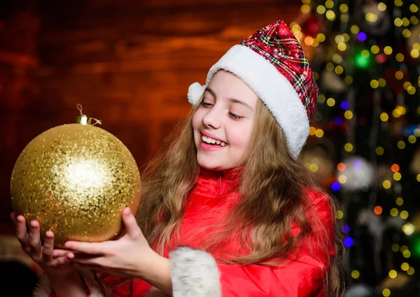 Love to decorate everything around. Sparkling big toy. Merry christmas. Festive atmosphere christmas day. Girl santa claus costume hold big ball christmas tree ornaments. Christmas decorations