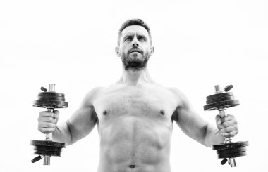 Halter egzersiz salonu. Dambılla egzersiz icra eden kaslı bir adam. Büyüklüğün bedeli sorumluluktur. Güçlü gövdeli sporcu. Spor aletleri. Fitness ve vücut geliştirme sporu. Spor salonu egzersiz konsepti