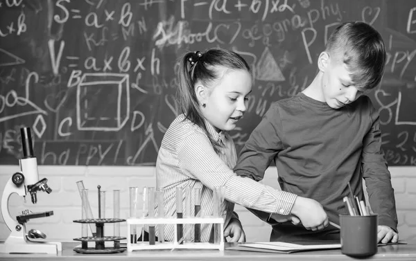 女の子と男の子のスマート学生は学校の実験を行います。化学分析。子供たちは化学を勉強する。化学の授業だ。学校の研究室。化学反応ノートパッドを説明します。学校教育 — ストック写真
