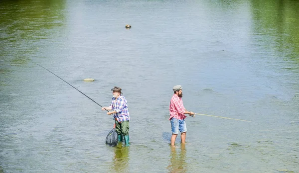 Fisket är mycket mer än fisk. Manlig vänskap. Far och son fiske. Sommar helgen. Lycklig fiskare med fiskespö och nät. Hobby-och idrottsaktiviteter. Fiske tillsammans. Män står i vatten — Stockfoto