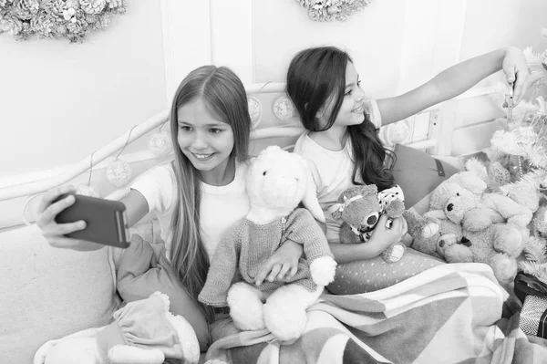 Imádom a szelfit. Karácsonyi és újévi szelfi okostelefonnal. A kislányok telefonálnak az ágyban. Boldog kisgyerekek mobiltelefonnal. Boldog karácsonyt és boldog új évet! — Stock Fotó