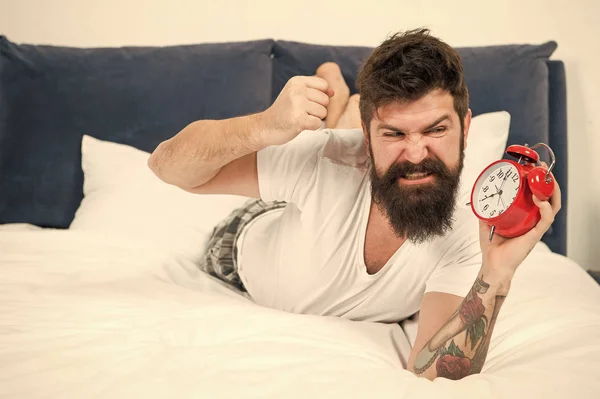 Se sentir stressé. Trop de bruit. homme barbu en colère écraser réveil. brutal homme agressif dans la chambre. mâle mature avec barbe sur le lit. endormi et réveillé. énergie et fatigue. gestion du temps — Photo