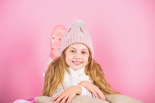 今年の冬を居心地の良い保つ暖かいアクセサリー。子供の女の子はリラックスピンクの背景をニット帽を着用。子供の長い髪暖かいウールの帽子は暖かいお楽しみください。暖かい服の概念。暖かく快適に — ストック写真