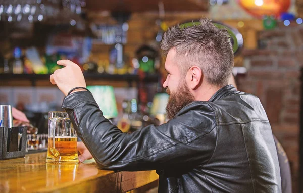 Homem com barba passar o lazer no bar escuro. Hipster relaxando no bar com cerveja. Homem barbudo hipster brutal senta-se no balcão do bar a beber cerveja. Sexta à noite. Bar é um lugar relaxante para tomar uma bebida e relaxar — Fotografia de Stock