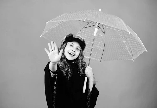 Ragazza felice tenere ombrello trasparente. Godetevi il tempo piovoso con indumenti adeguati. Gli accessori impermeabili rendono divertente la giornata piovosa. Godetevi il concetto di pioggia. Stagione autunnale. Tendenza moda bambini. Amore giorni di pioggia — Foto Stock